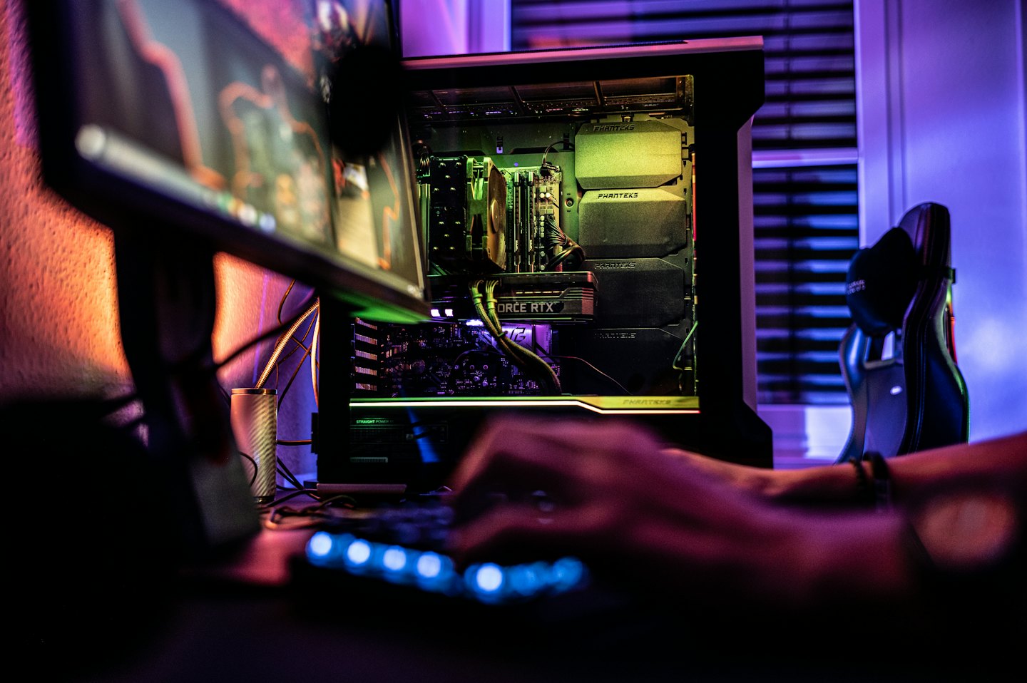 Hände tippen auf einer leuchtenden mechanischen Tastatur, die mit einem Computer verbunden ist.