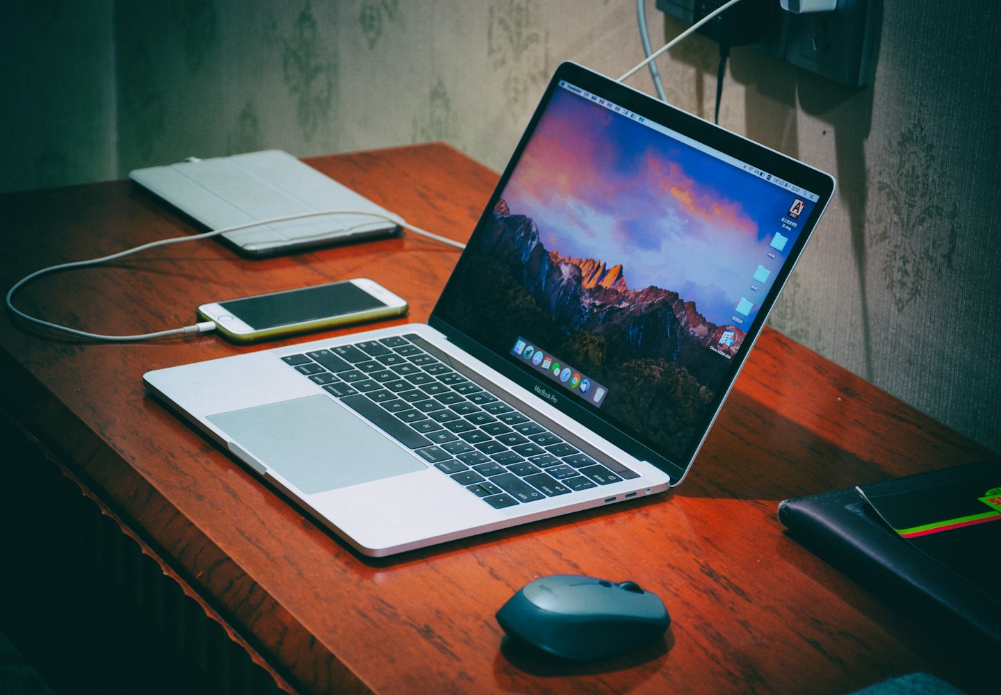 Laptop mit Berg-Hintergrund auf einem Holztisch mit Handy und Tablet.